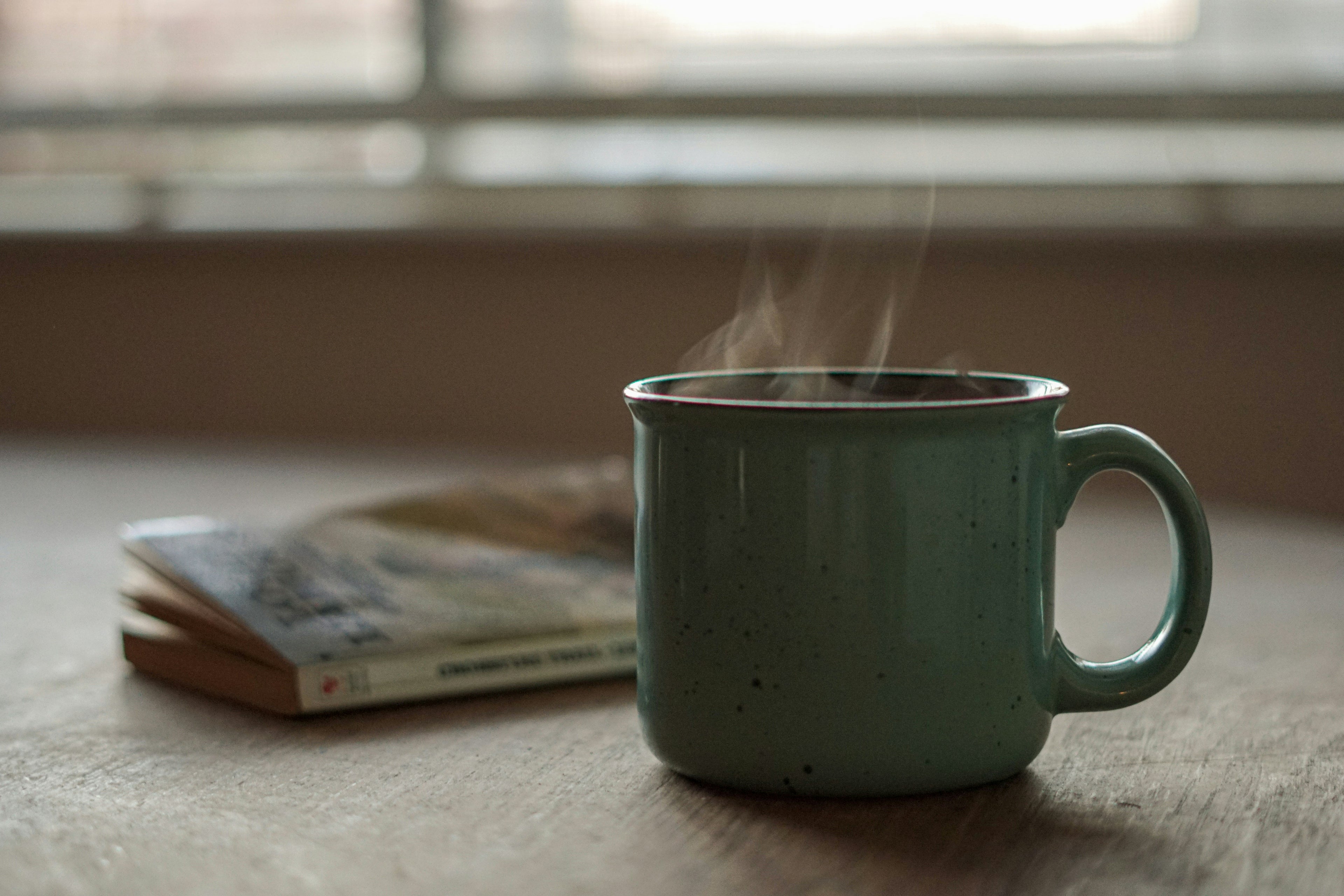 Steaming green mug on a wooden surface with a blurred background